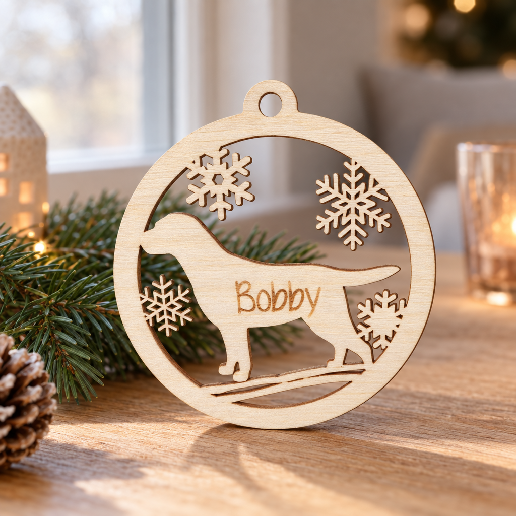 Ronde houten kerstbal met de vorm van een hond, sneeuwvlokken en de naam Bobby gegraveerd.