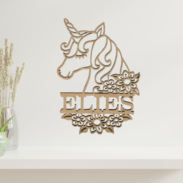 Houten muurdecoratie in de vorm van eenhoorn met bloemen en een gepersonaliseerde naam.
