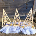 Drie houten kerstboompjes met gesneden sterren en kerstballen met gepersonaliseerde namen in natuurlijke houtkleur.