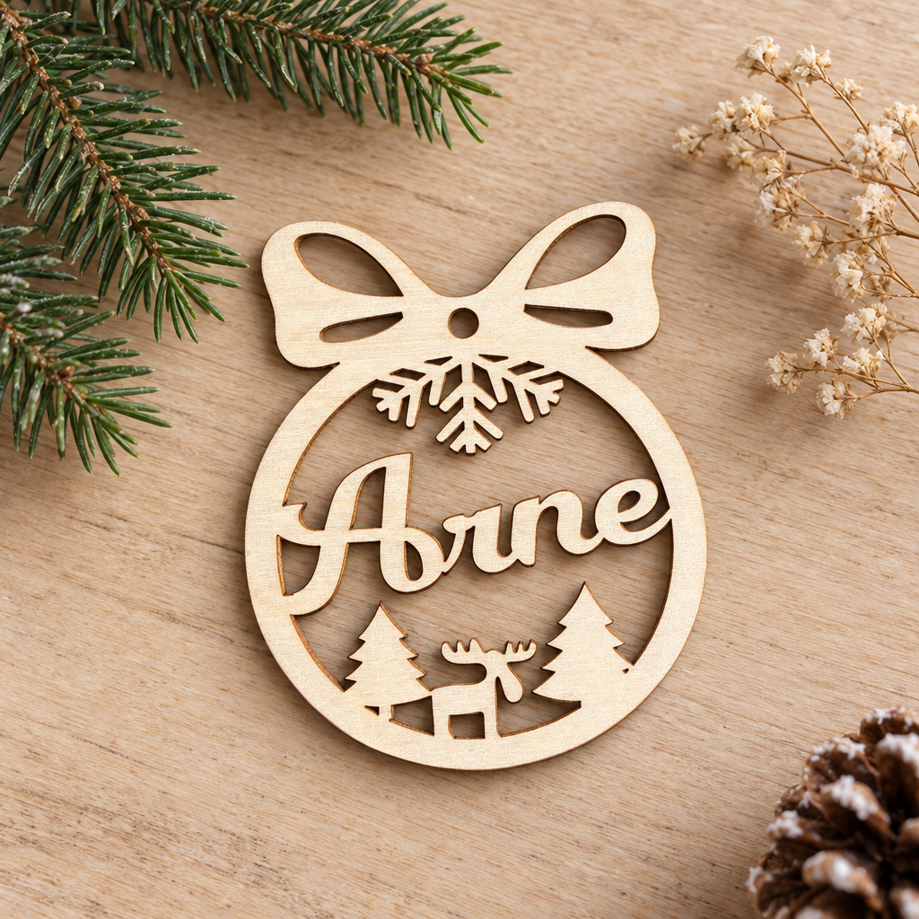 Houten kerstbal met uitgesneden strik, sneeuwvlok, rendier, dennenbomen en de naam Arne in het midden.