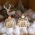 Twee houten kerstballen in de vorm van truitjes met gegraveerde namen Emma en Lucas en winters motief.