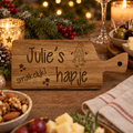Klein rechthoekig houten hapjesplankje met handvat, gegraveerde tekst "Julie’s hapje smakelijk!" en een tekening van een kerstkabouter.