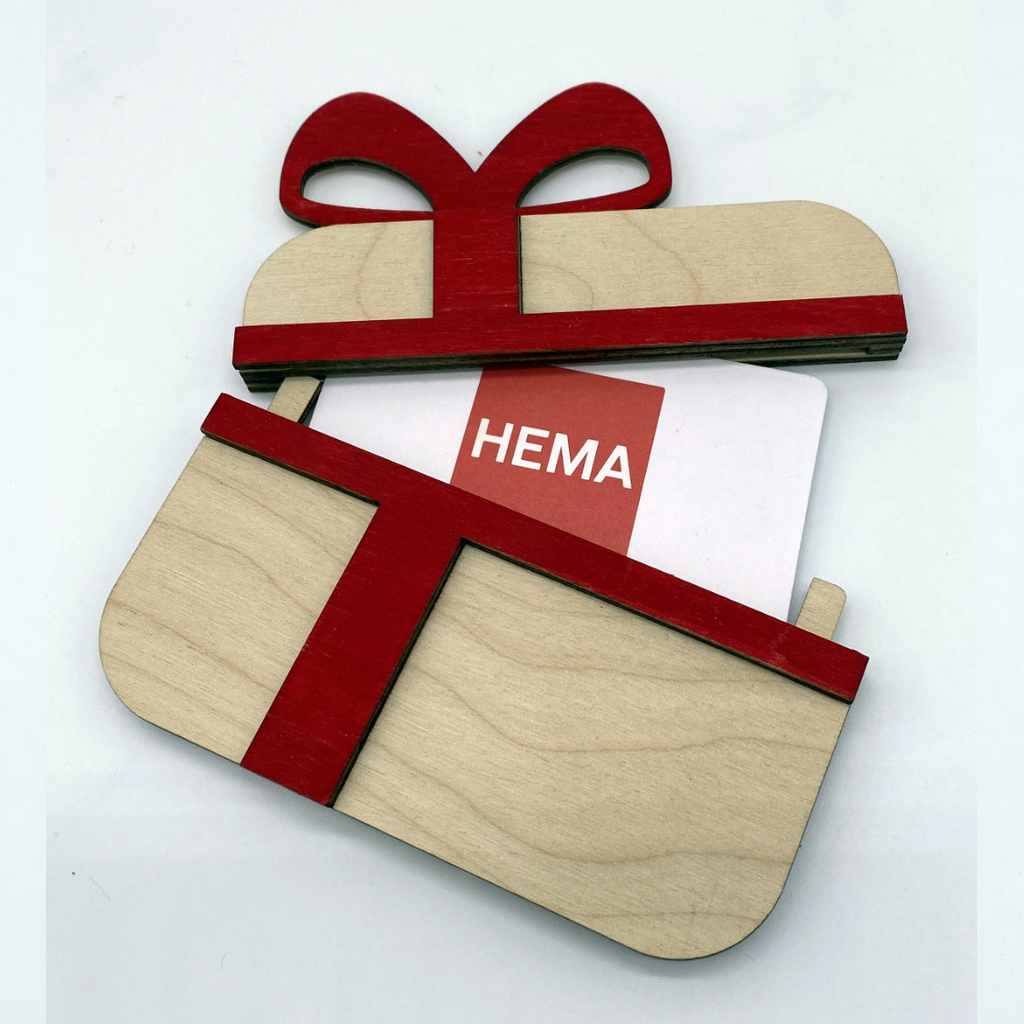 Houten geschenkverpakking in de vorm van een lichtbruine cadeautje met een rood houten strik en lint, opengeklapt met een cadeaubon erin.