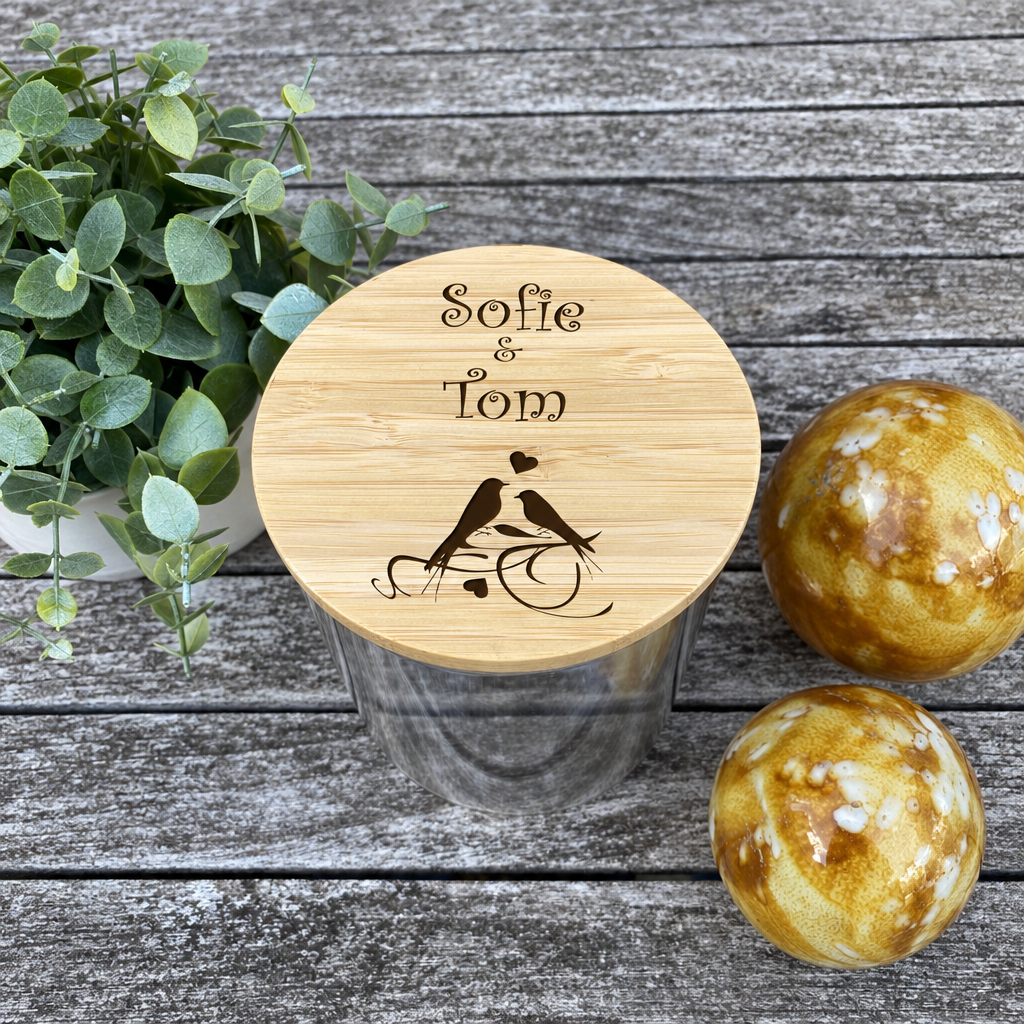 Ronde glazen snoeppot met een houten deksel met gegraveerde vogels en een gepersonaliseerde tekst.